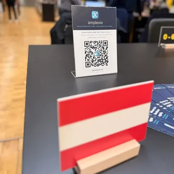 Display with a QR code reading “Scan now and get on a call”, an Austrian flag in the foreground